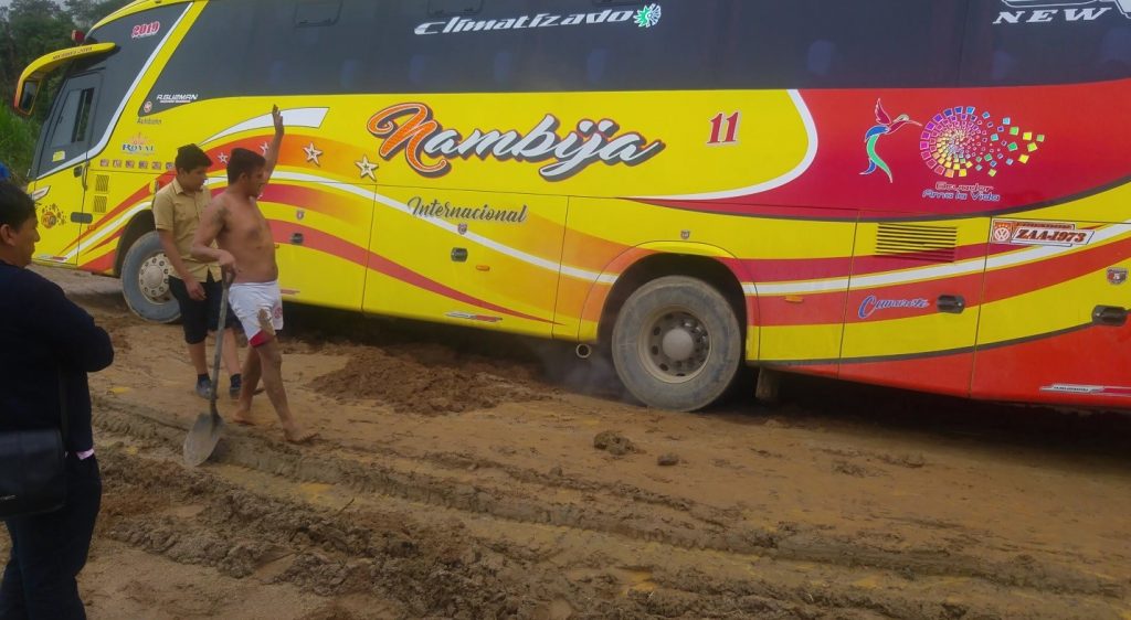 Bus driver digging bus out of mud