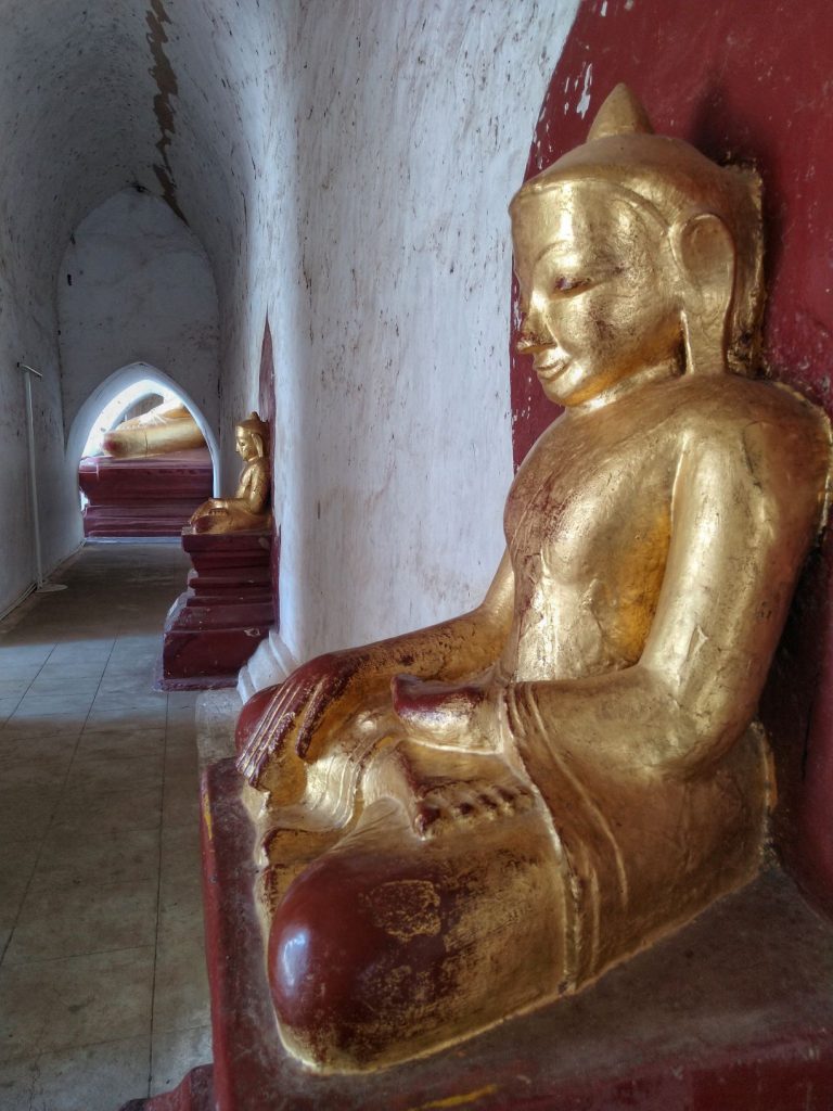 Golden Buddha statues in a temple corridor in Myanmar